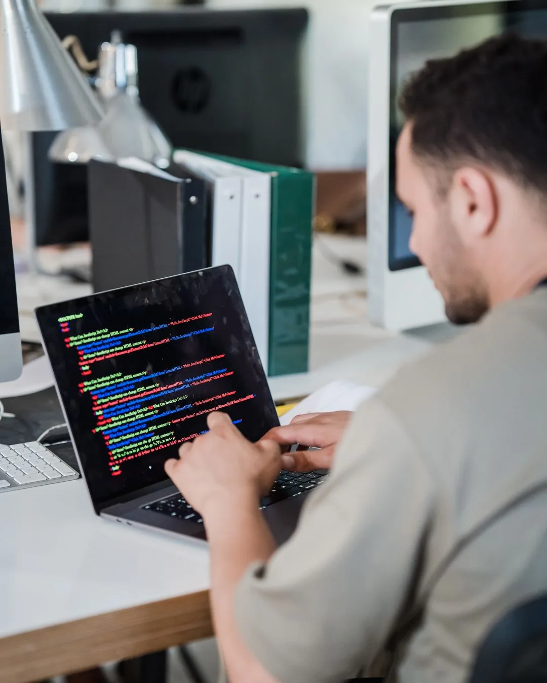 Eine Person schreibt konzentriert Programmcode auf einem Laptop.